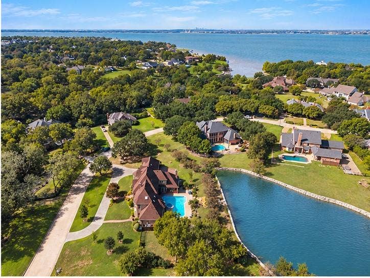 508 Moraine Way, Heath, TX 75032 Aerial perspective of a sprawling residential lot featuring a private waterfront pond, an in-ground swimming pool, manicured grounds, and mature tree coverage