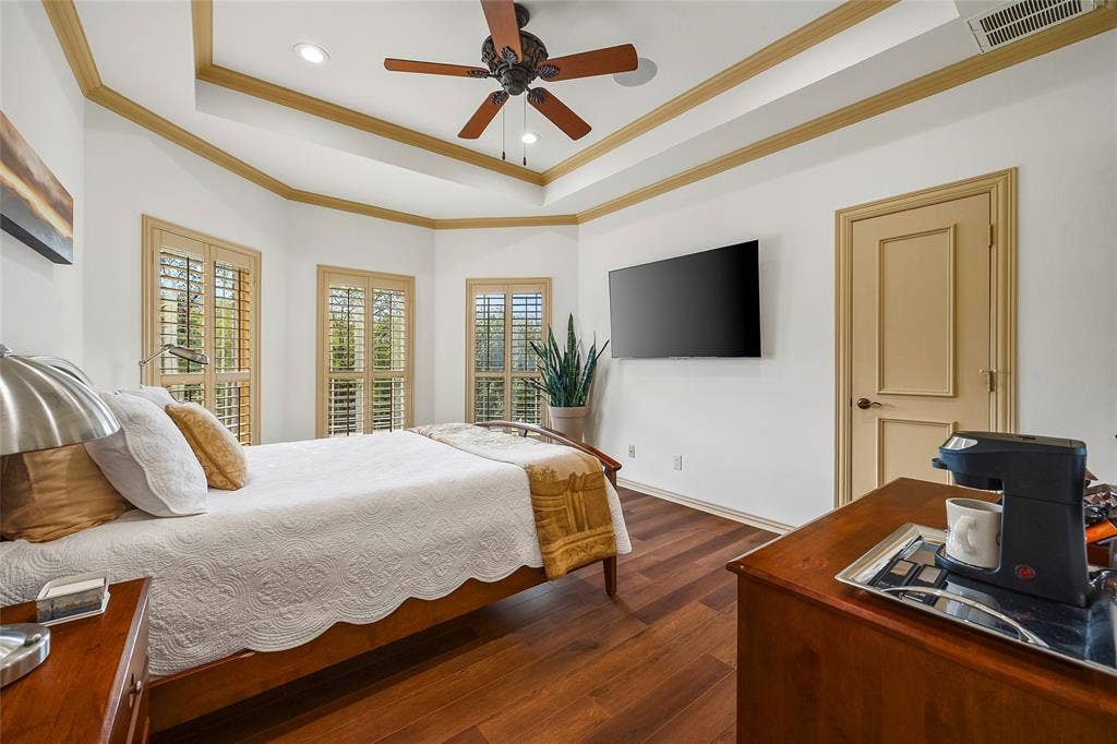 508 Moraine Way, Heath, TX 75032 Inviting bedroom featuring a tray ceiling, wood flooring, and ample natural light.