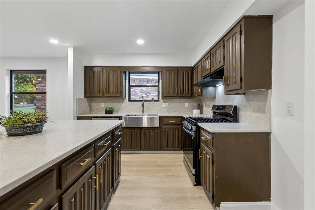 2133 Oak Valley Lane, Dallas, TX 75232 Kitchen with wood-finish cabinetry, light-toned countertops, stainless steel sink, and light wood-finish flooring