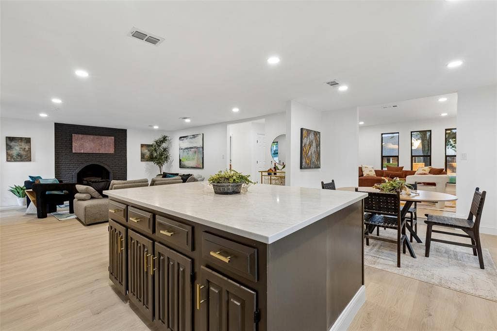 2133 Oak Valley Lane, Dallas, TX 75232 Central kitchen island with a stone countertop and dark wood cabinetry