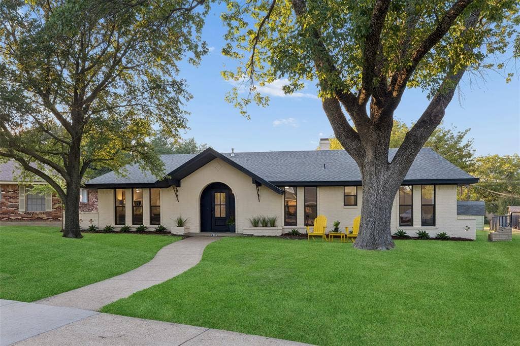 2133 Oak Valley Lane, Dallas, TX 75232 brick exterior with an arched entryway, dark trim windows, and a dark shingled roof