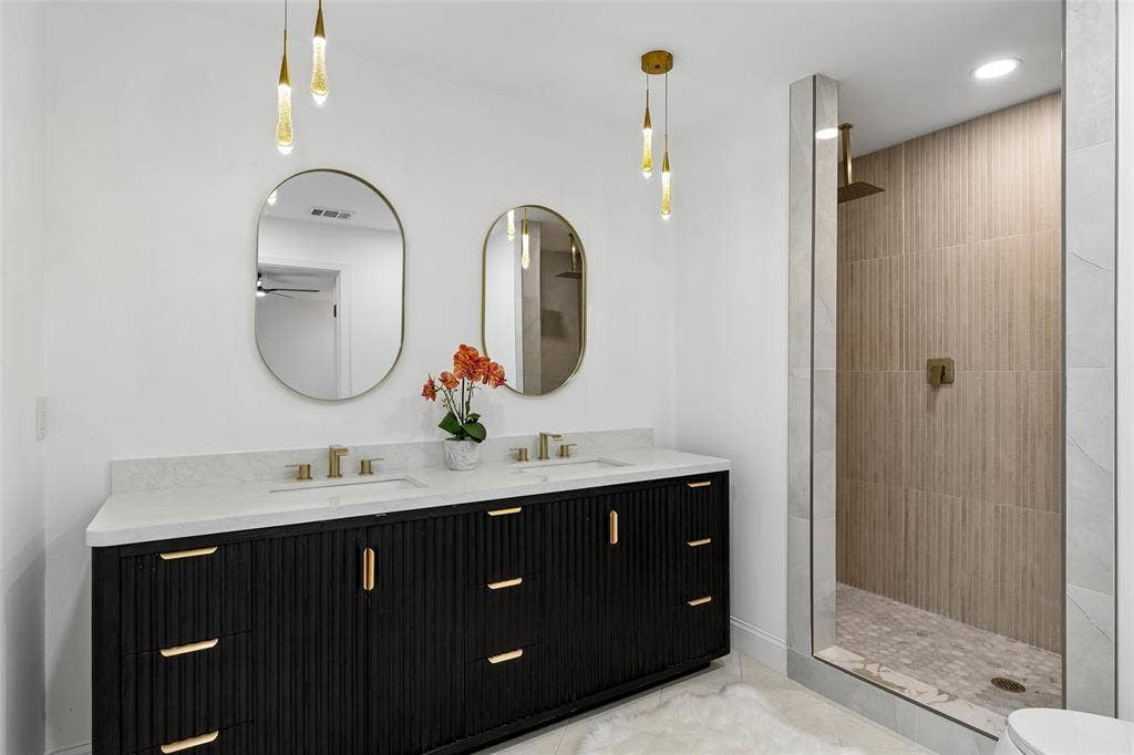 2133 Oak Valley Lane, Dallas, TX 75232 Dual vanity with a fluted dark wood-finish cabinet and gold-tone hardware