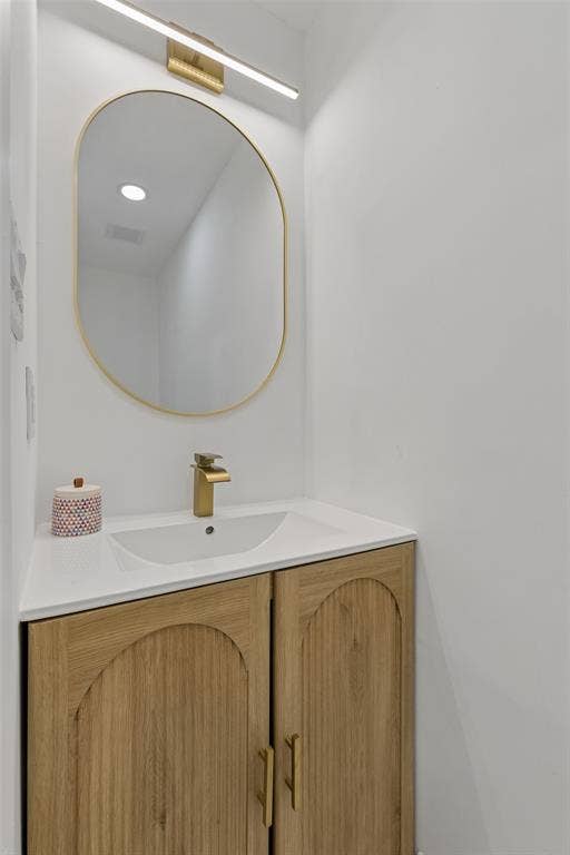 2133 Oak Valley Lane, Dallas, TX 75232 Wood-finish vanity with arched details, gold-finish hardware, and a white countertop with an integrated sink