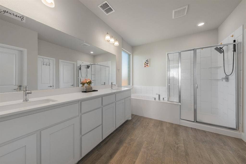 Bathroom with a bath, a shower stall, double vanity, dark wood-style floors, and recessed lighting