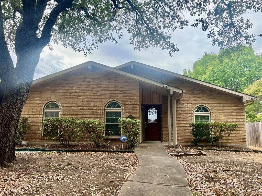 3925 Villa Downs Drive, Plano, TX 75023 Brick exterior with arched windows, covered entryway, and mature trees