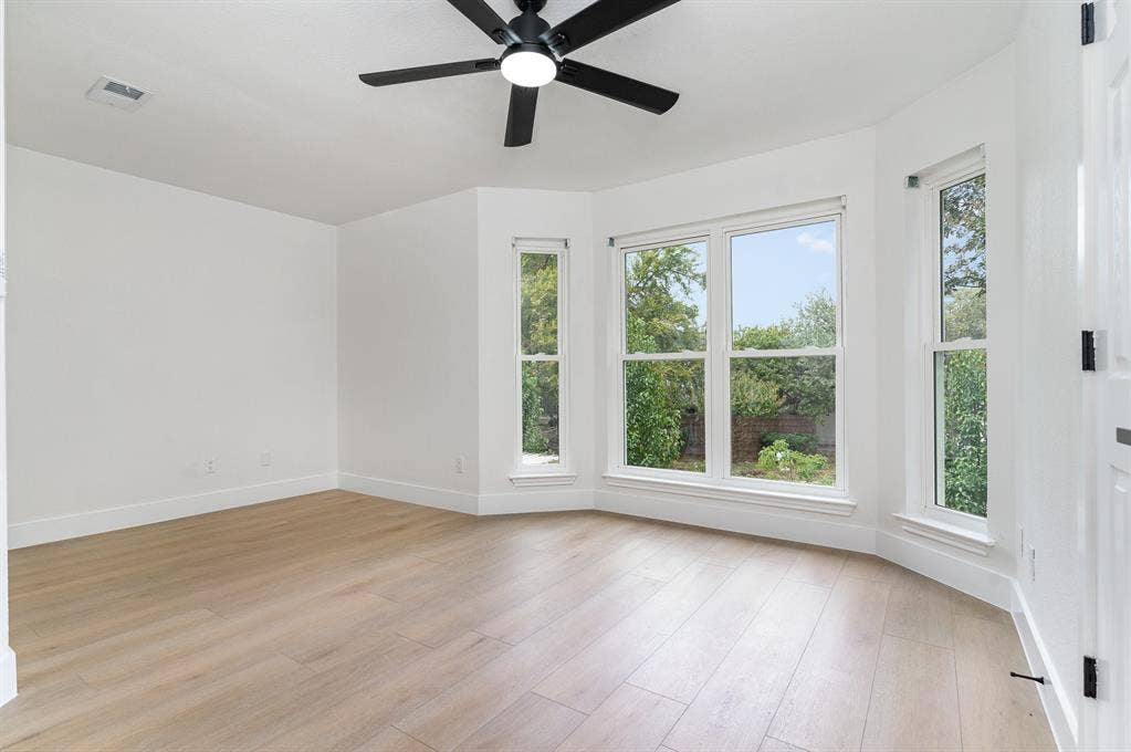 17732 Windflower Way, Dallas, TX 75252 Empty room with a wealth of natural light, light hardwood / wood-style floors, and ceiling fan