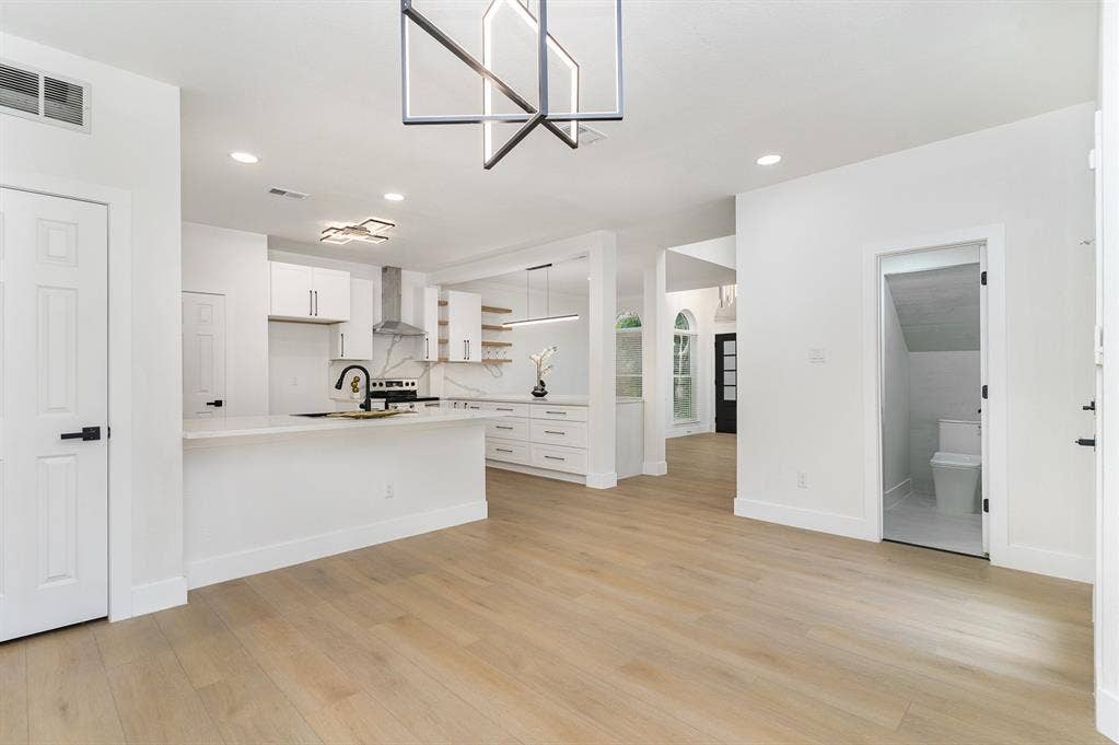 17732 Windflower Way, Dallas, TX 75252 Kitchen featuring light wood-type flooring, white cabinetry, kitchen peninsula, and wall chimney range hood