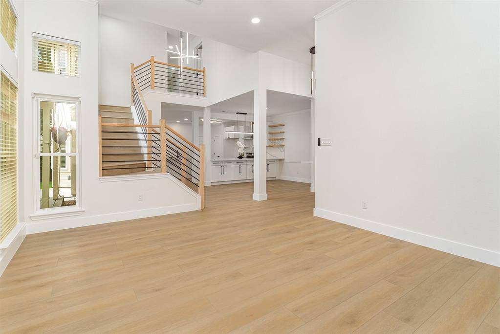 17732 Windflower Way, Dallas, TX 75252 Unfurnished living room with a wealth of natural light, a high ceiling, and light wood-type flooring