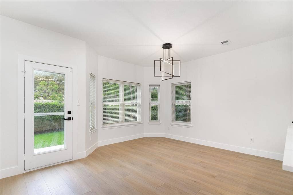 17732 Windflower Way, Dallas, TX 75252 Unfurnished dining area featuring light wood-type flooring and a notable chandelier