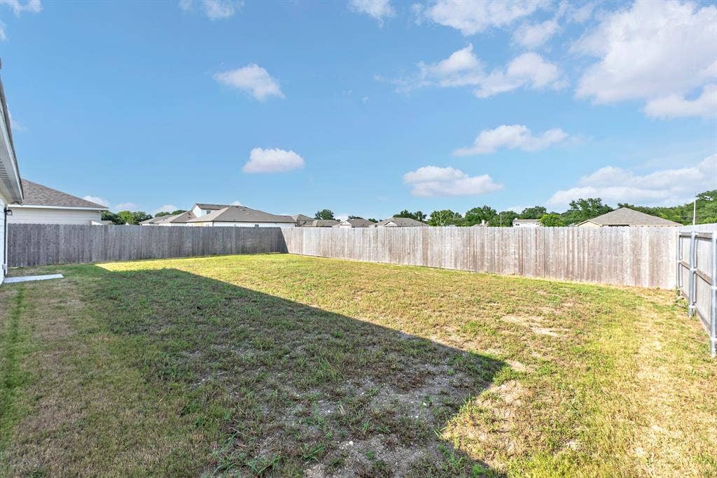Expansive backyard featuring a natural grass lawn and wood privacy fencing