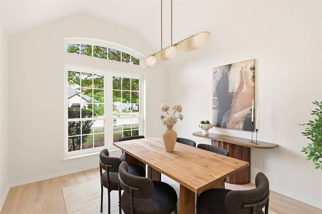 Vaulted ceiling, arched transom window, large grid-patterned window, wood-finish flooring, and a linear pendant light fixture