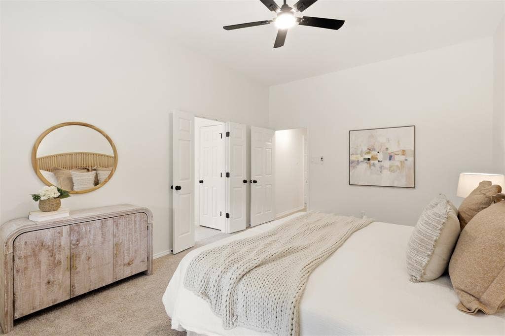 White walls, carpet flooring, a ceiling fan with light, and bi-fold doors