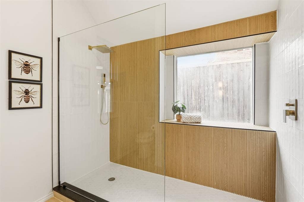 Glass-enclosed shower with a rainfall showerhead, handheld shower fixture, and a built-in window