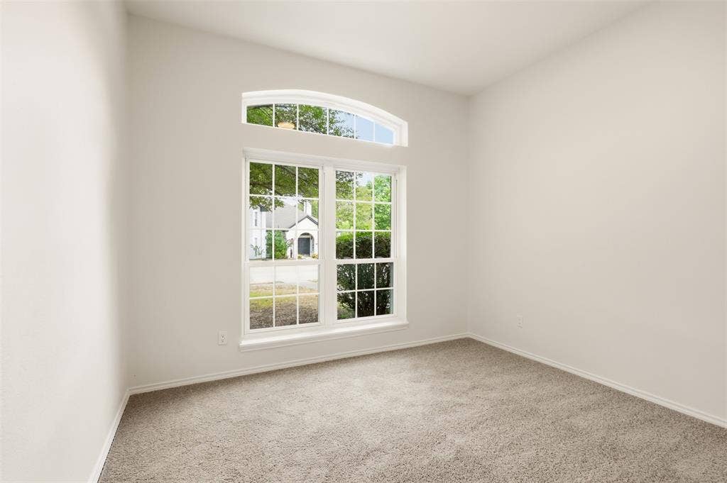 Neutral wall color, arched transom window, picture windows, and gray carpeting