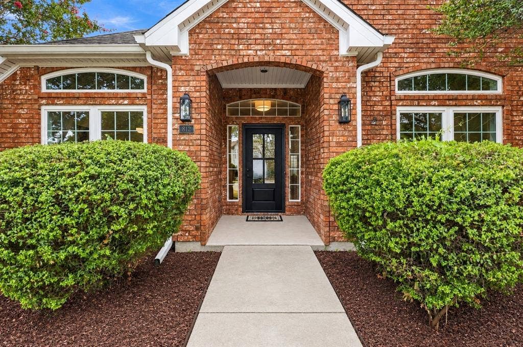 Brick facade with arched entry, transom windows, and symmetrical decorative lighting