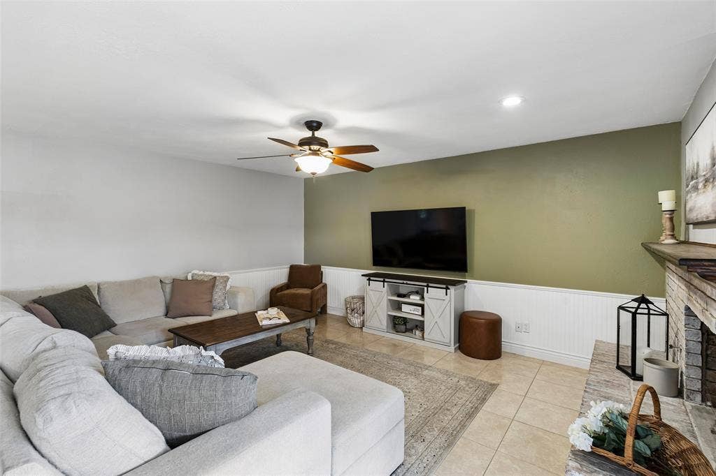 4021 Overdowns Drive, Plano, TX 75023 A soft green accent wall pairs with the brick fireplace for an easy, low-key living room feel.