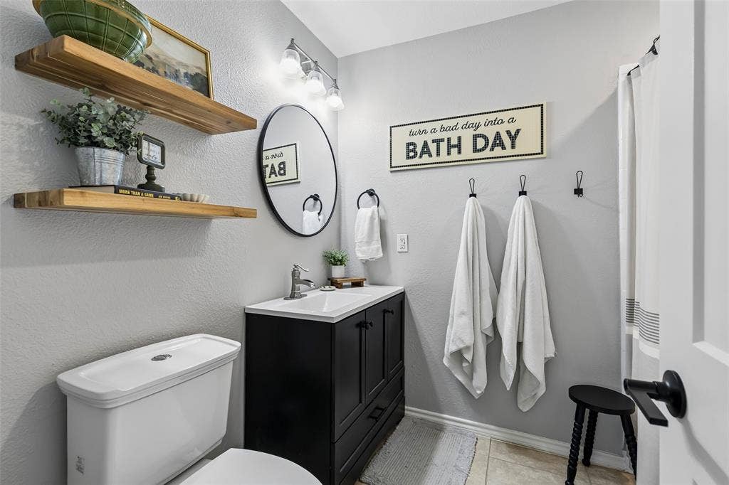 4021 Overdowns Drive, Plano, TX 75023 A round mirror and black hardware keep the hall bathroom's single vanity simple and functional.