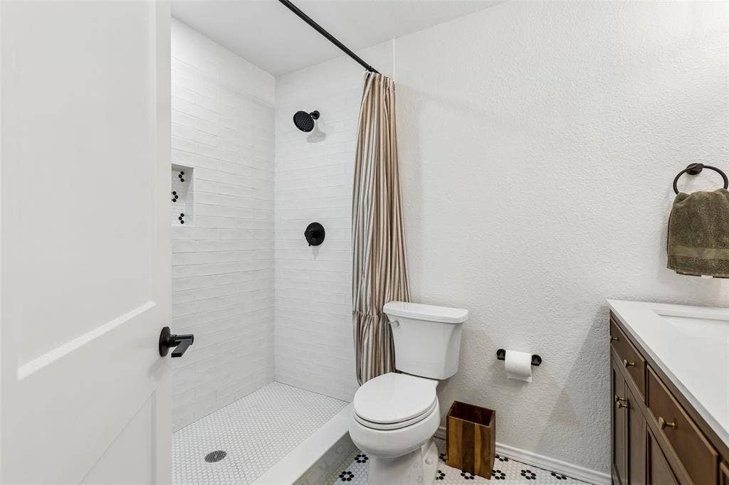 4021 Overdowns Drive, Plano, TX 75023 A tiled niche and matte-black fixtures dress up the hall bath's shower without losing everyday function.