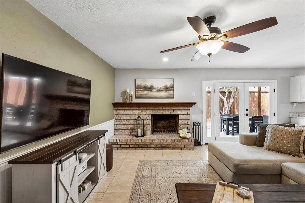 4021 Overdowns Drive, Plano, TX 75023 A fireplace anchors the main gathering space, framed by French doors that open straight onto the covered patio.