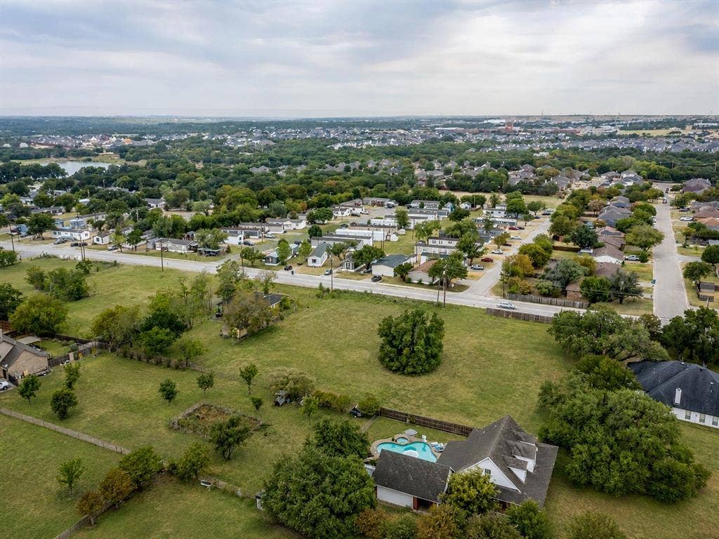 0 Old Annetta Road, Aledo, TX 76008 Expansive grounds featuring mature trees and a fenced perimeter, alongside a residential structure with a gabled roof and an in-ground swimming pool