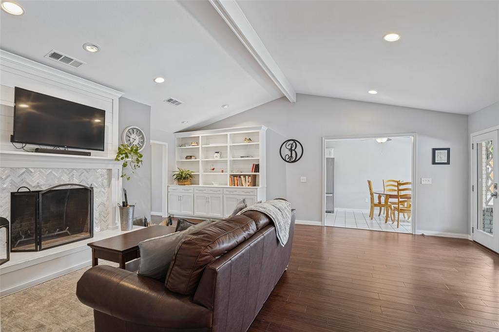 3632 Candelaria Drive, Plano, TX 75023 Vaulted ceiling with exposed beams, wood-finish flooring, built-in shelving, fireplace with decorative tile surround, and recessed lighting