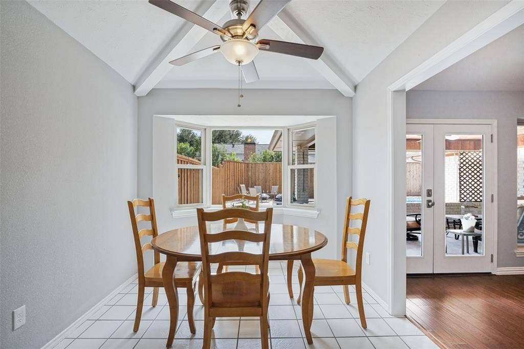 3632 Candelaria Drive, Plano, TX 75023 Vaulted ceiling with exposed beams, ceiling fan light fixture, bay window, white tile flooring, and double French doors with glass panels