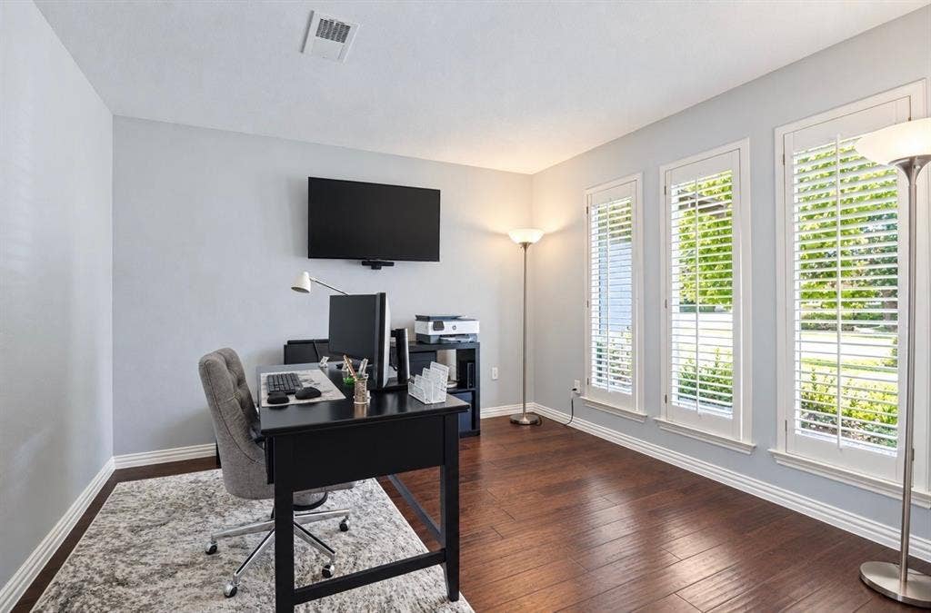 3632 Candelaria Drive, Plano, TX 75023 Hardwood-finish flooring, light grey wall paint, and white window shutters across multiple windows