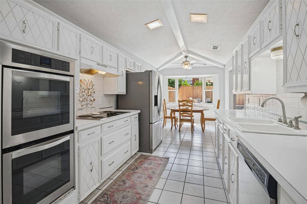 3632 Candelaria Drive, Plano, TX 75023 Galley kitchen featuring white cabinetry, tile flooring, stainless steel double ovens, and a built-in dishwasher