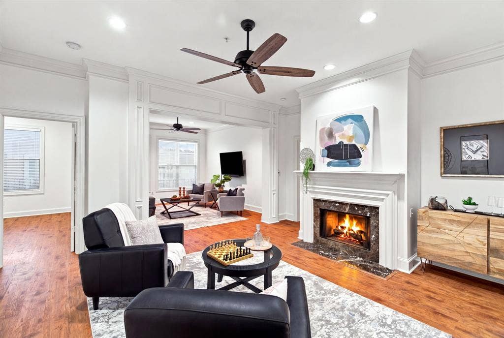 3303 Blackburn Street, #306, Dallas, TX 75204 Hardwood-finish flooring, a decorative fireplace with a marble-finish surround, crown molding, a ceiling fan, and recessed lighting