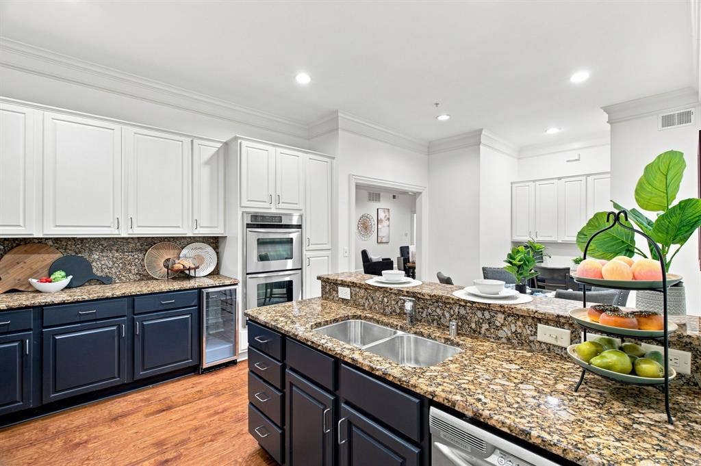 3303 Blackburn Street, #306, Dallas, TX 75204 Kitchen featuring granite countertops, stainless steel double wall ovens, a dual basin stainless steel sink, and wood-finish flooring