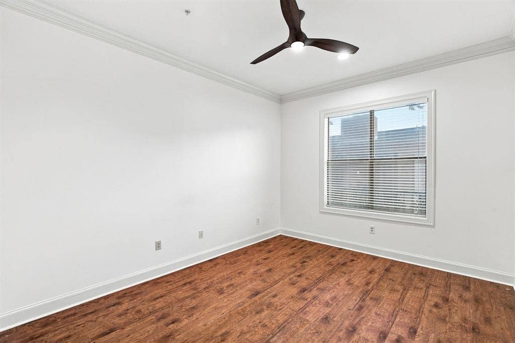 3303 Blackburn Street, #306, Dallas, TX 75204 Guest bedroom with wood-finish flooring, white walls, crown molding, a window with blinds, and a dark-toned ceiling fan with integrated lighting