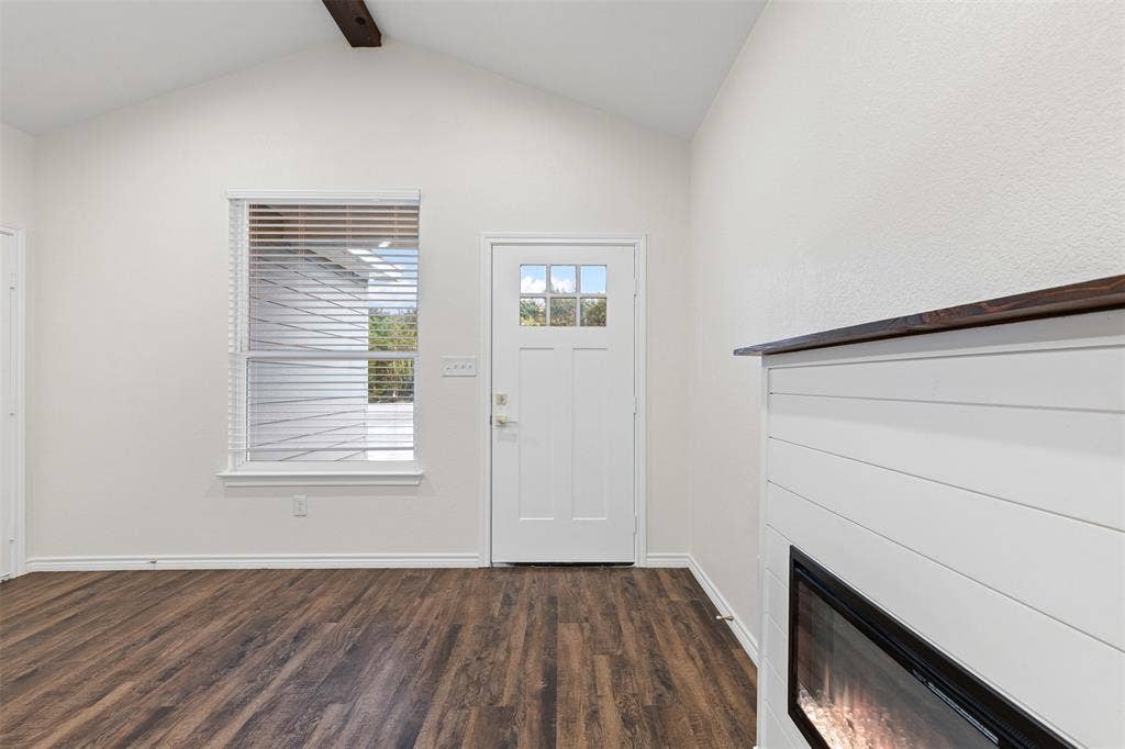 Entrance foyer featuring dark wood-style floors, baseboards, and a glass covered fireplace