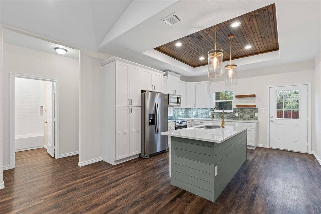Kitchen featuring a tray ceiling, stainless steel appliances, open shelves, baseboards, and wood ceiling