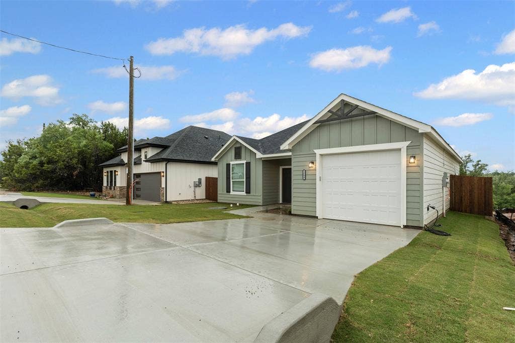 Single story home featuring board and batten siding, a shingled roof, concrete driveway, and a garage