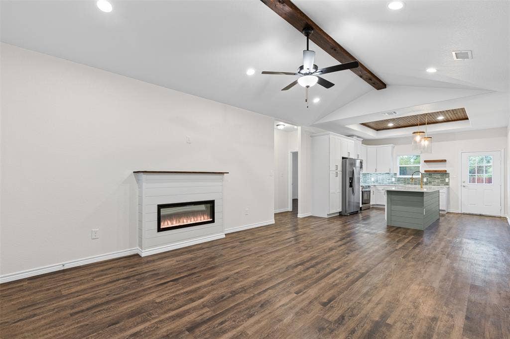 Unfurnished living room featuring recessed lighting, dark wood-style flooring, a glass covered fireplace, ceiling fan, and baseboards