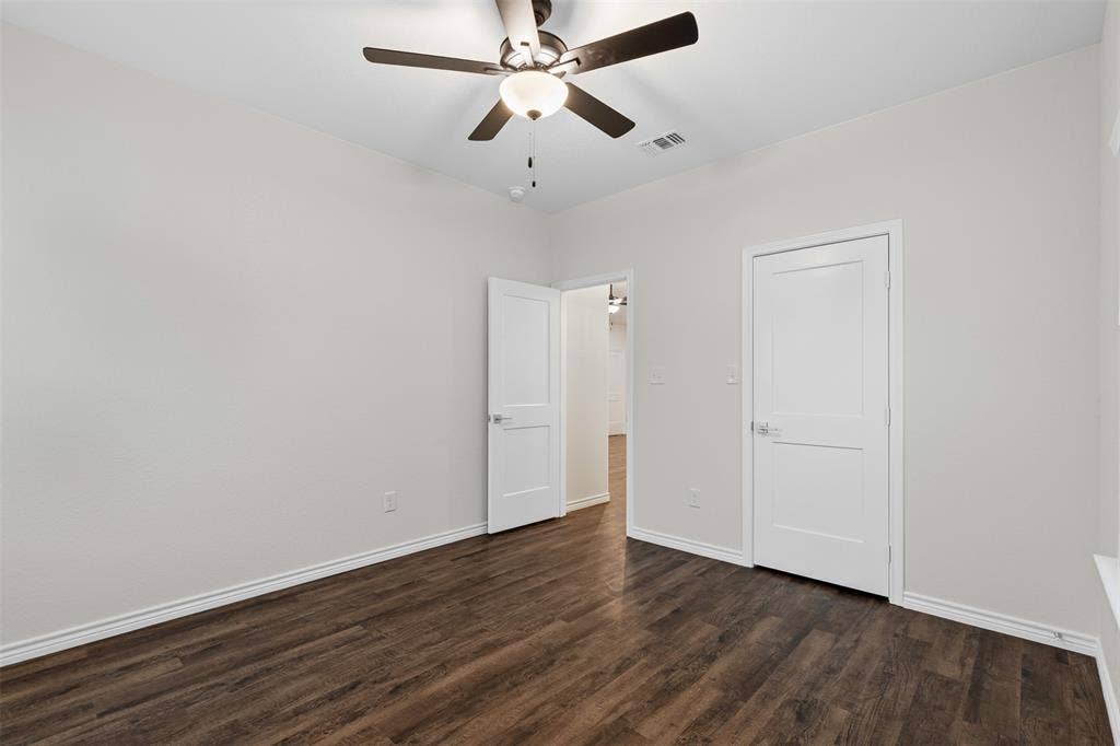 Unfurnished bedroom with dark wood-type flooring, baseboards, and a ceiling fan