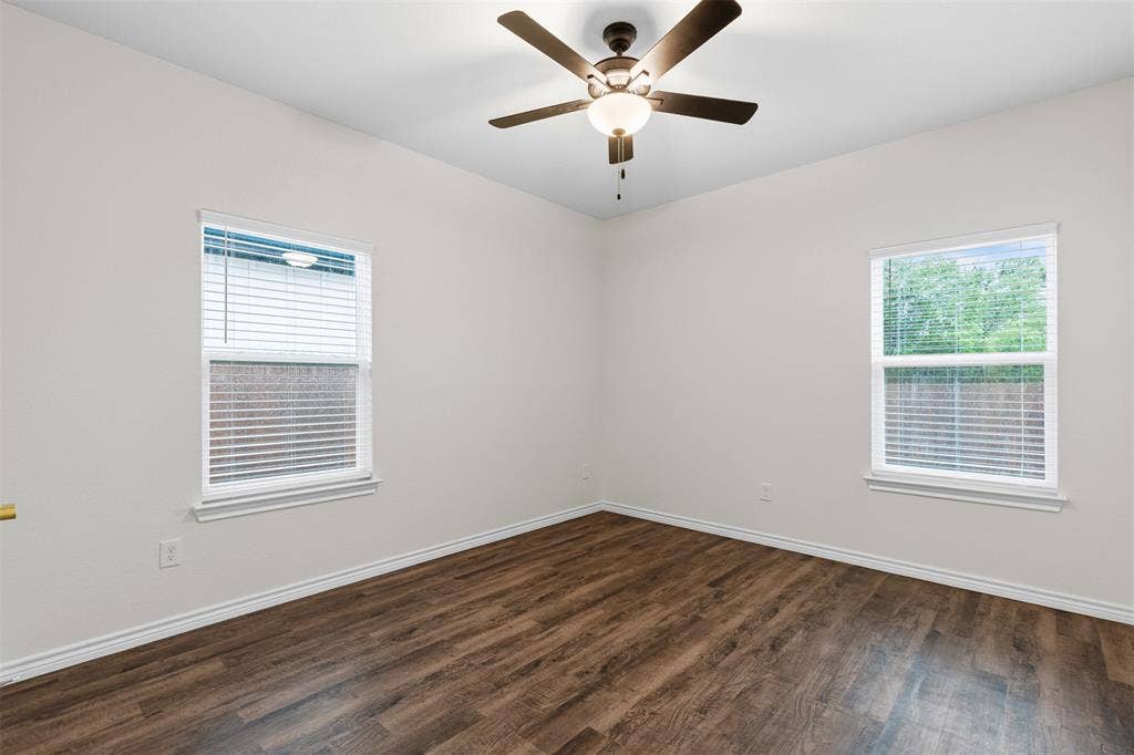 Empty room featuring dark wood finished floors, baseboards, and ceiling fan