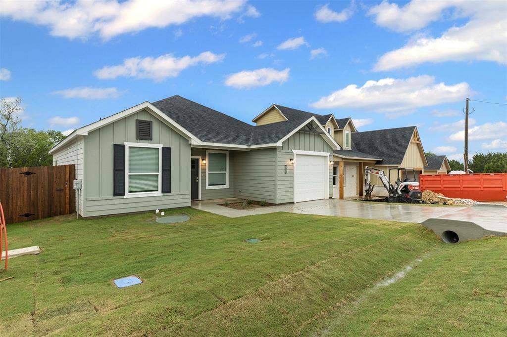 View of front facade featuring board and batten siding, driveway, a garage, and roof with shingles