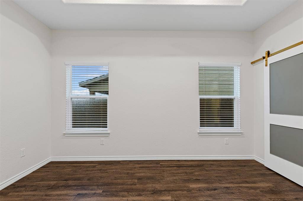 Spare room featuring wood finished floors, baseboards, and a barn door