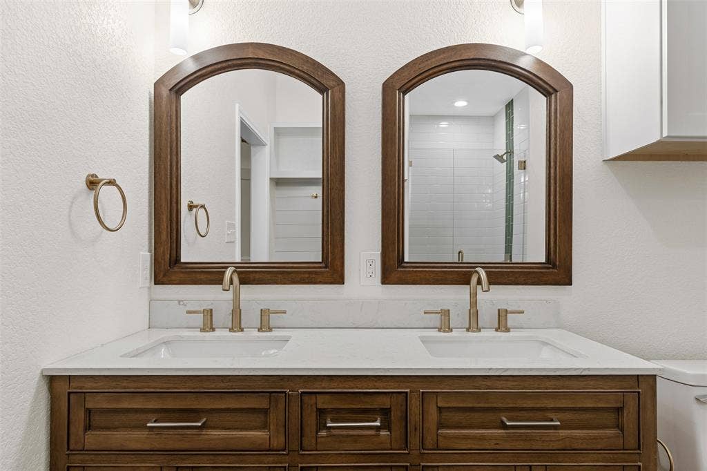 Bathroom featuring double vanity, toilet, and a shower