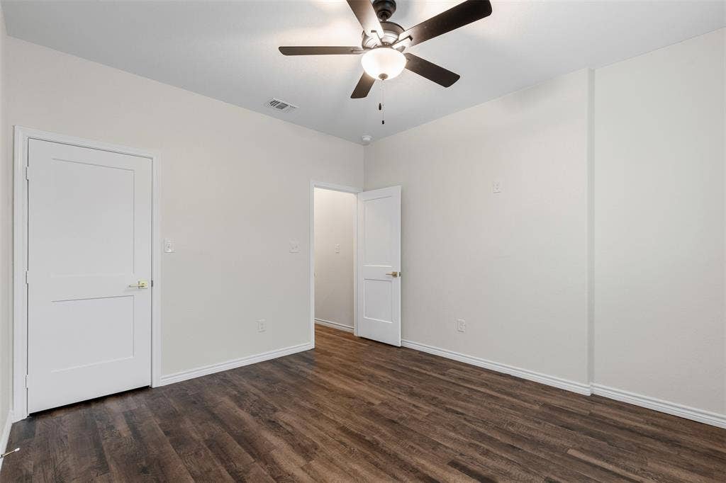 Unfurnished bedroom featuring dark wood finished floors, baseboards, and a ceiling fan