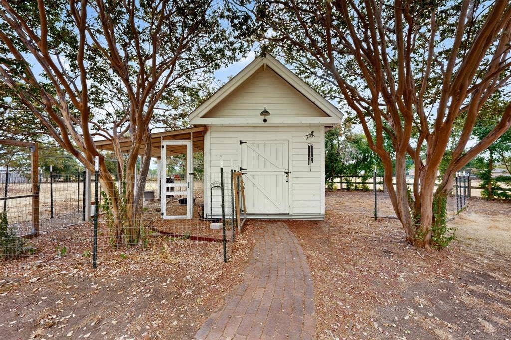 2 Trailridge Drive, Melissa, TX 75454 White wood-paneled outbuilding with a gable roof, barn-style door, and attached covered extension