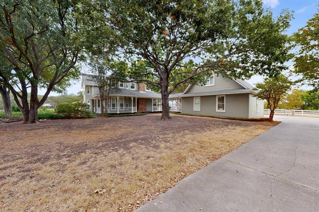 2 Trailridge Drive, Melissa, TX 75454 Two-story residence with a wrap-around porch, brick chimney, and dormer windows, complemented by a detached structure with a white fence