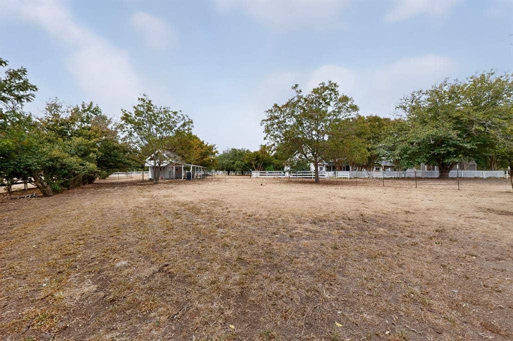 2 Trailridge Drive, Melissa, TX 75454 Expansive outdoor area with a white picket fence, mature trees, and a visible outbuilding