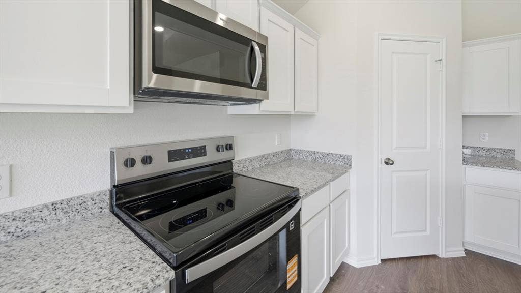1972 Freeman Street, Tyler, TX 75704 Kitchen featuring white cabinetry, light-toned countertops, a stainless steel microwave, and a black electric range with stainless steel accents