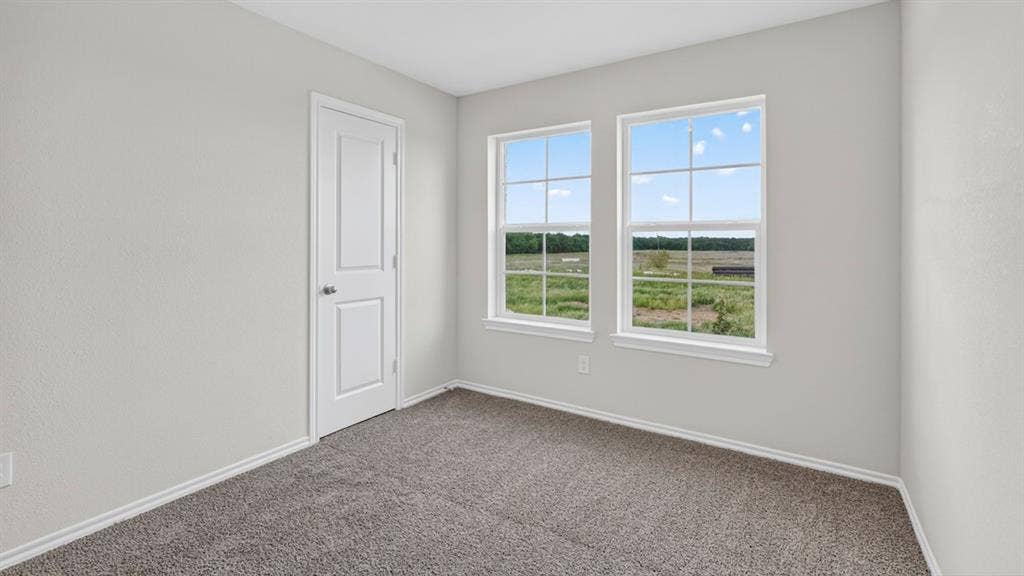 1920 Freeman Street, Tyler, TX 75704 Room with light gray walls, gray carpet, and two large windows offering extensive outdoor scenery