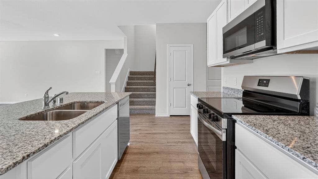 1920 Freeman Street, Tyler, TX 75704 Kitchen featuring white cabinetry, stainless steel appliances, a double basin sink, and wood-finish flooring