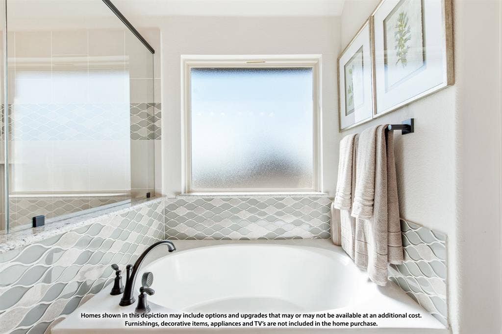942 Cardinal Drive, Midlothian, TX 76065 White soaking tub featuring a matte black faucet, surrounded by a wave-patterned tile and a frosted window