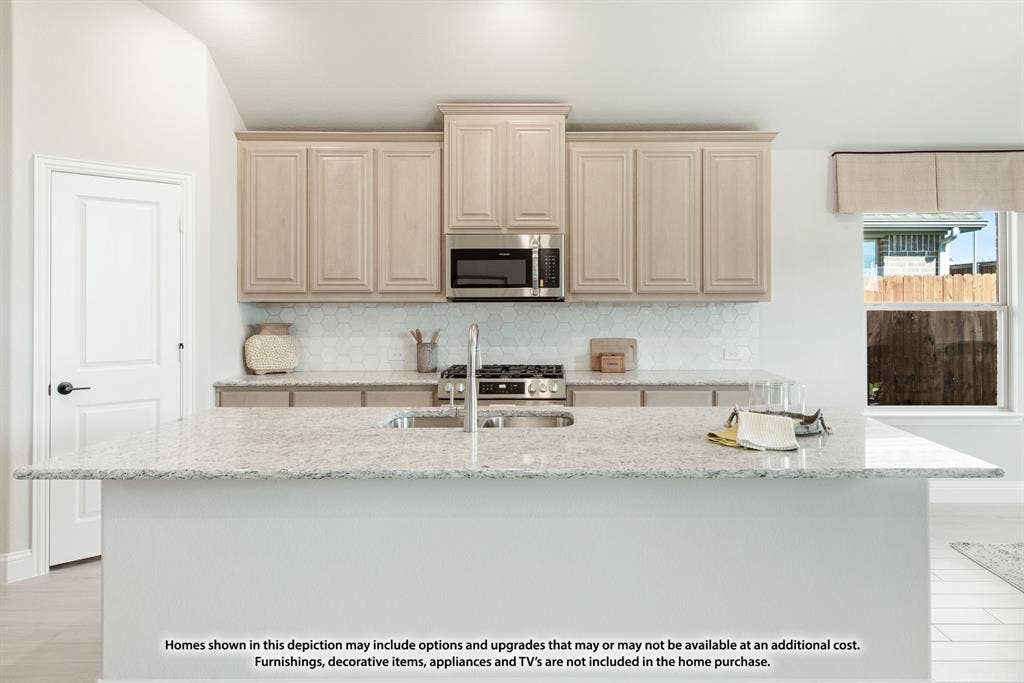 942 Cardinal Drive, Midlothian, TX 76065 Kitchen featuring a large center island with a stainless steel sink, light-toned cabinetry, stainless steel microwave, and a gas range