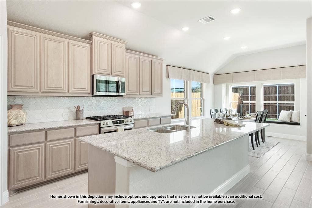 942 Cardinal Drive, Midlothian, TX 76065 Kitchen featuring a large island with a dual-basin sink, light-toned cabinetry, stainless steel microwave, and gas range